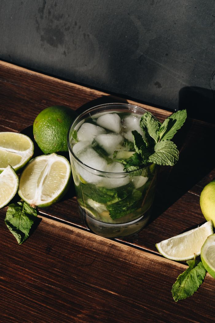 A cool and refreshing mojito with fresh lime and mint on a wooden table.